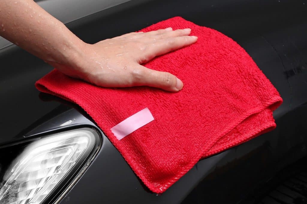 hand wiping refrigerator interior with cloth