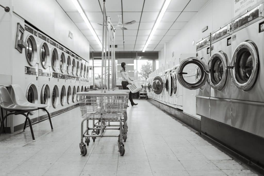 person cleaning drum washing machine interior with brush and oxygen bleach