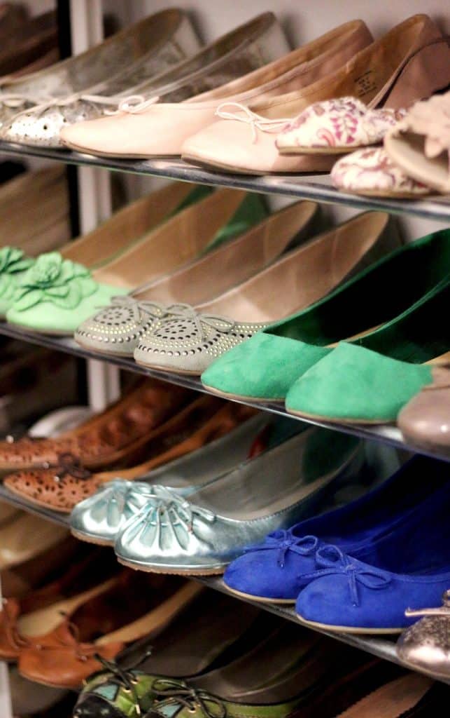 open shoe cabinet with organized sneakers and charcoal bags on bottom shelf
