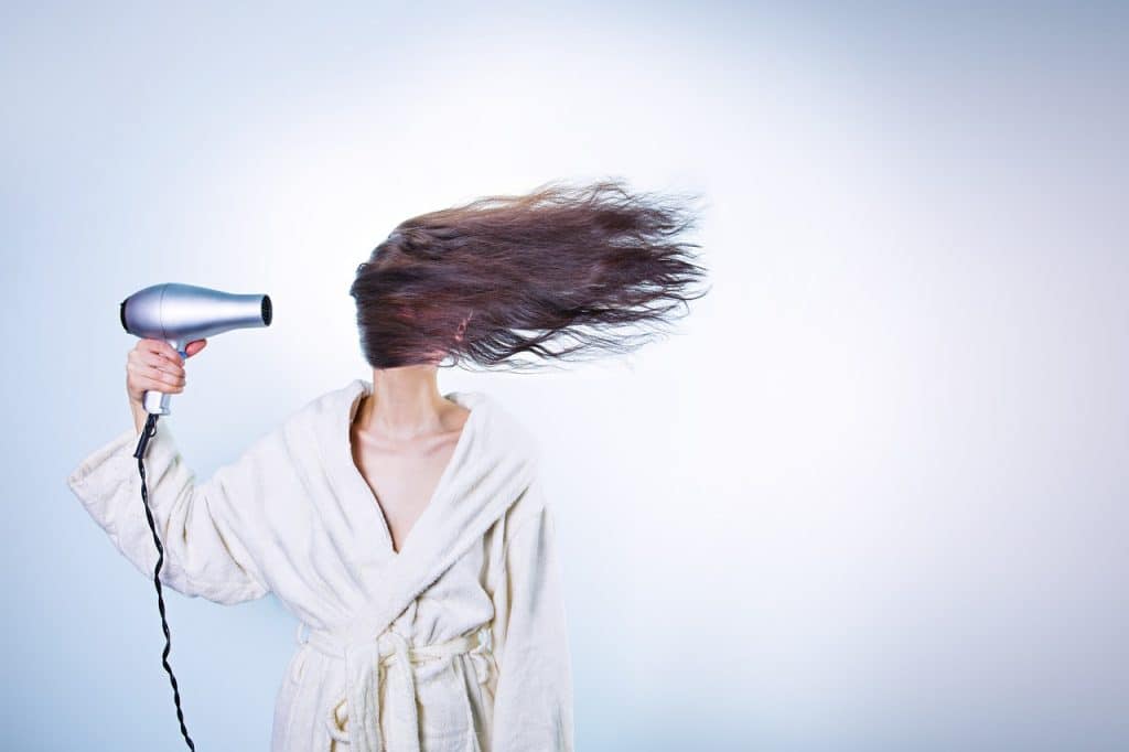 person using hair dryer to melt freezer frost carefully