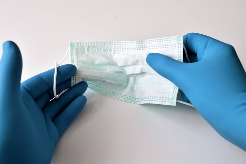 latex gloves hand placing wet paper towel on bathroom caulk