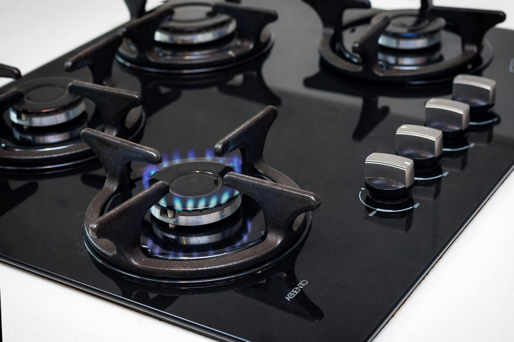weekly kitchen cleaning routine with microfiber cloth on gas stove