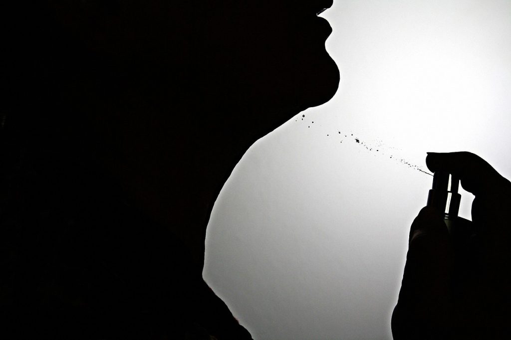 spray bottle with diluted dish soap being sprayed on glass