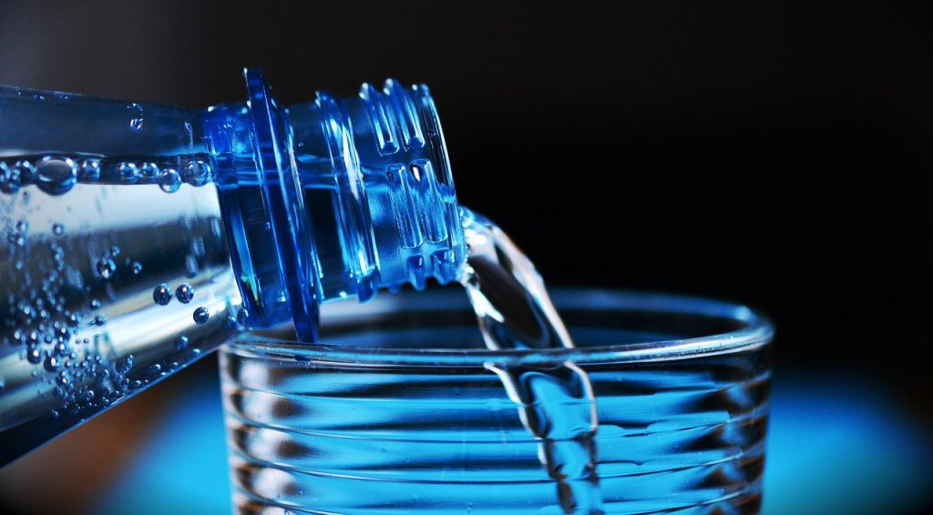 white vinegar poured into plastic container with water