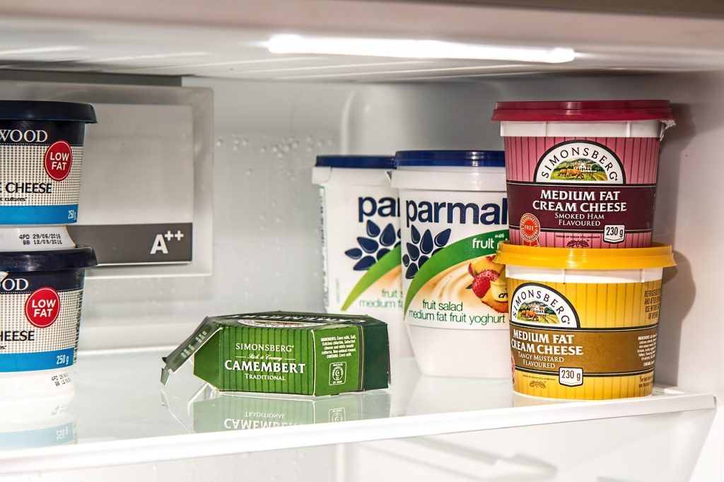 caulking gun sealing gap behind refrigerator in kitchen