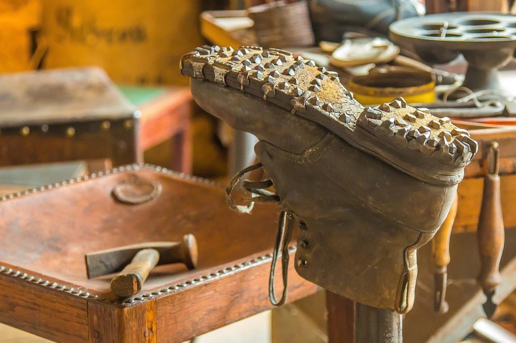 cobbler repairing heel of dress shoe at repair shop