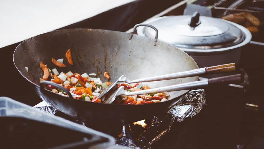 woman fluffing rice right after cooking with wooden spatula