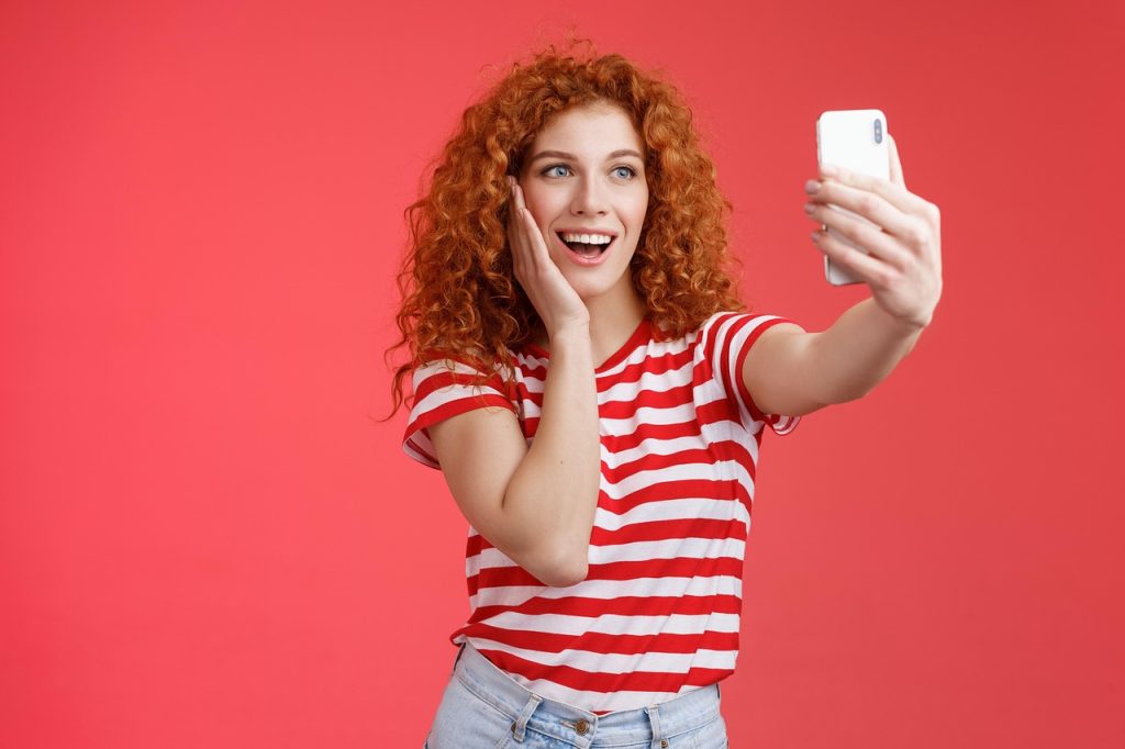young man receiving bank notification of large transfer on smartphone, smiling