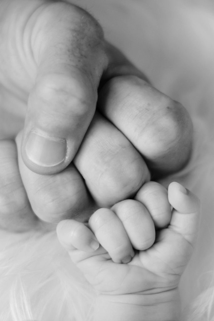 family with newborn baby smiling at home surrounded by paperwork and support documents
