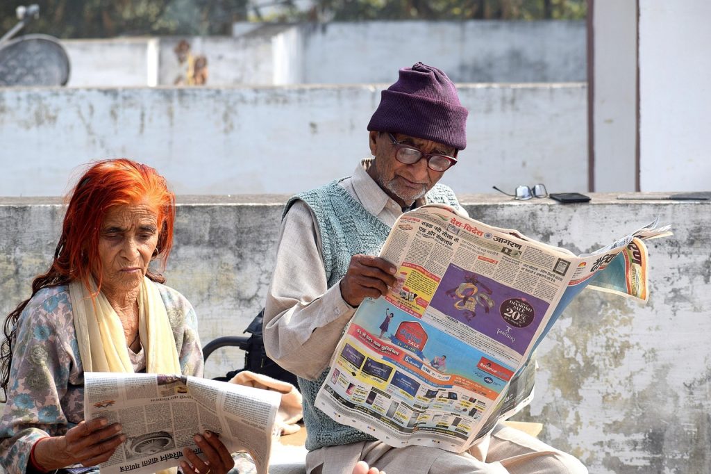 elderly Korean man reading newspaper at public library