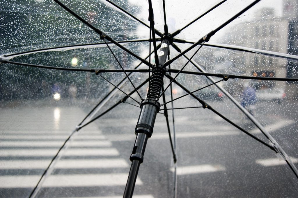 small umbrella protecting a tiny business shop model from rain