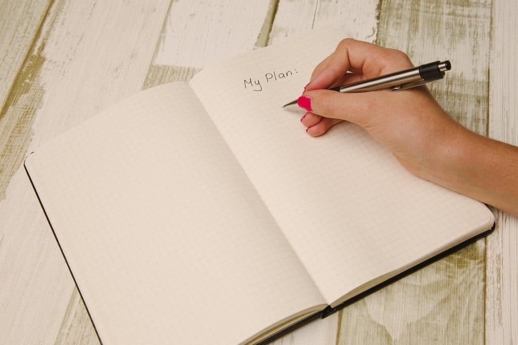 woman writing notes in a planner with job application documents