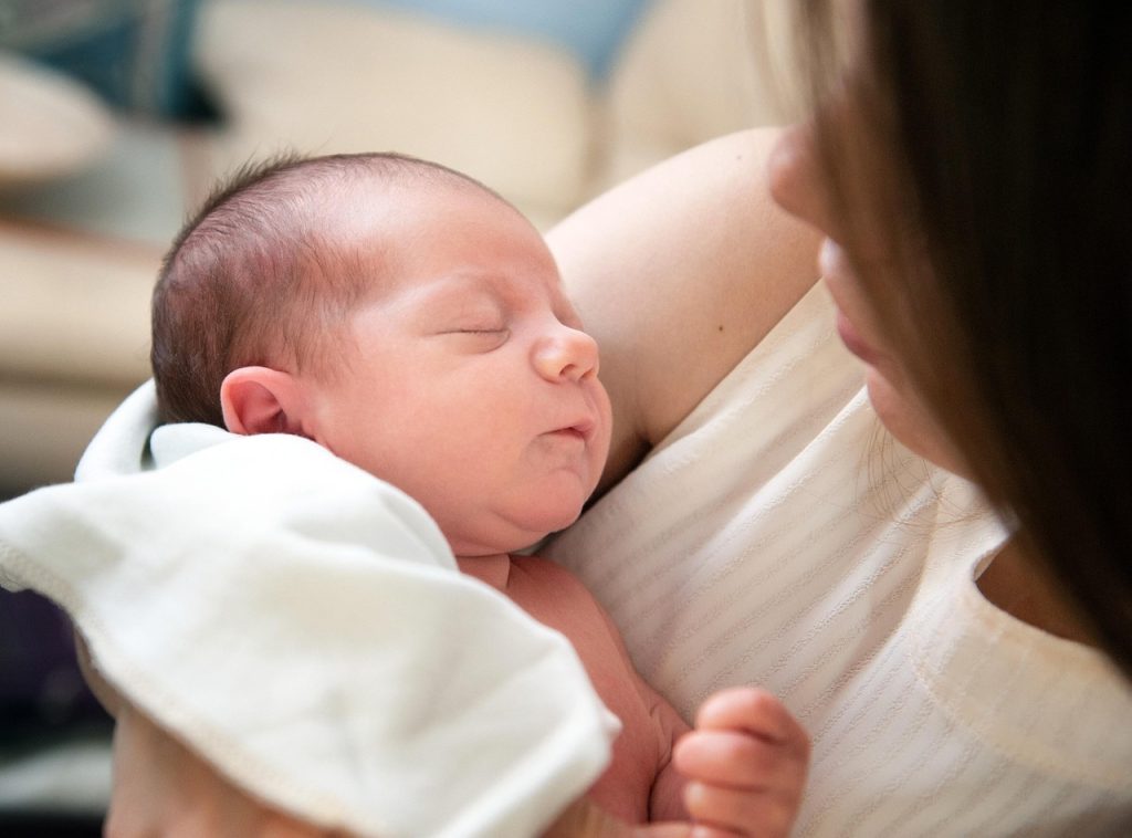 Korean working mother holding newborn baby at home in natural light