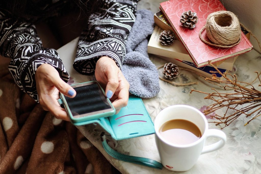 smartphone showing a scholarship website with warm coffee cup beside it